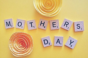 mothers day spelled out on yellow background using scrabble tiles.