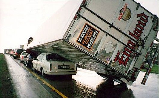 Funny Pictures of Transport Truck Leaning on a Cadillac