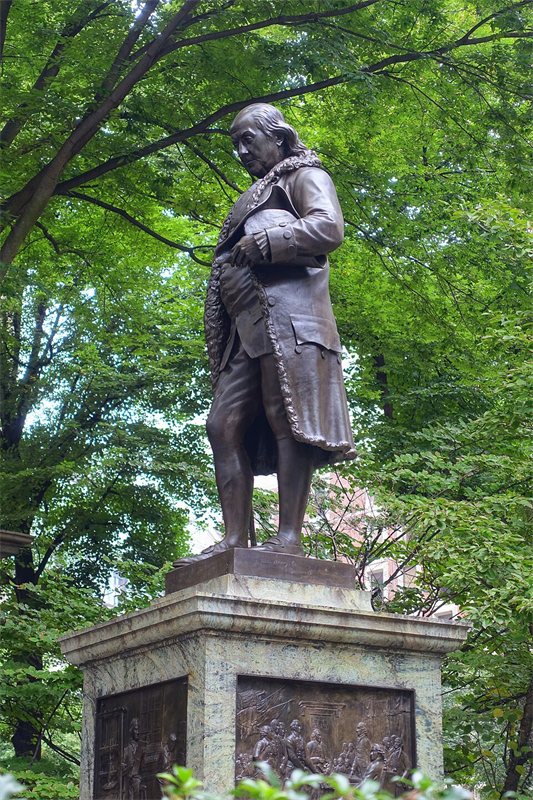 A statue of Benjamin Franklin on a stone pedestal.
