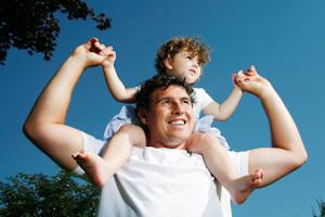 A dad gives his daughter getting a shoulder ride.