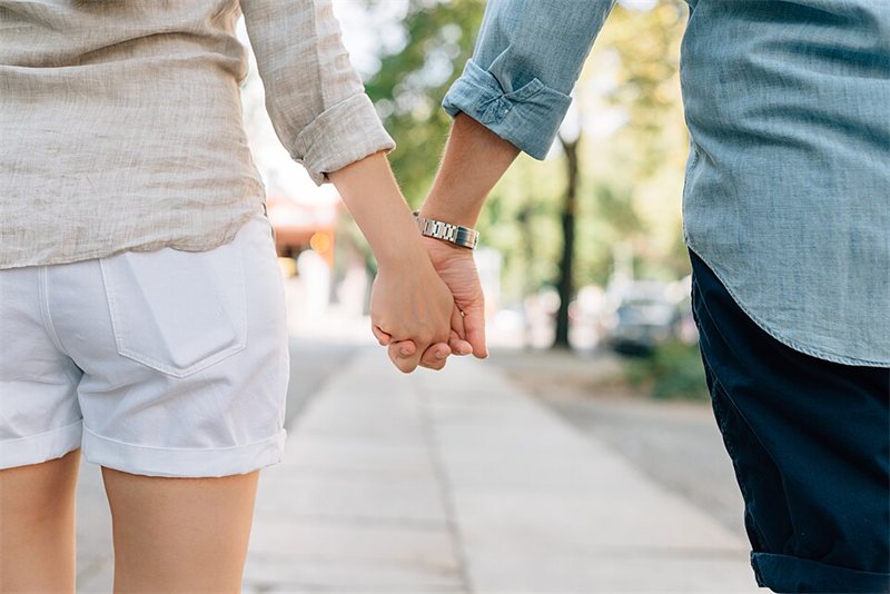 Two people holding hands as they walk.