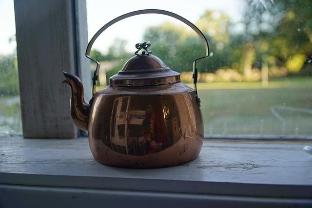 A copper kettle sitting on a window sill.