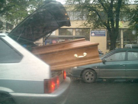A casket sticking out of a car.