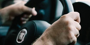 A close-up of two hands on a steering wheel.
