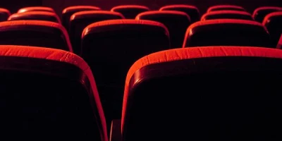 Empty red movie theatre seating as seen from the back looking towards the front.